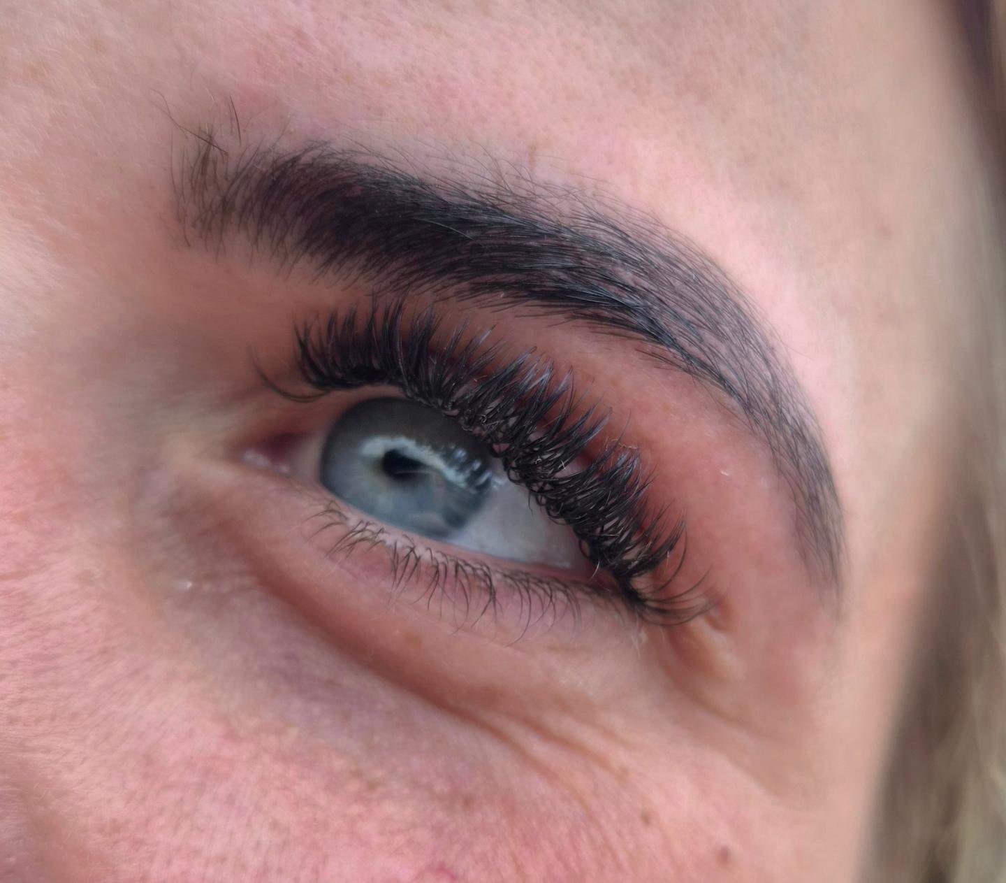 Volle wimperextensions bij een blauw oog, met donkere wenkbrauw